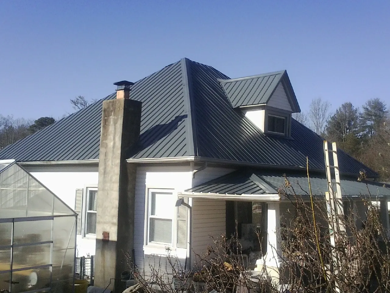 Dark blue standing seam metal roof on a white farmhouse with dormer — Slate & Tile Roof Repair by Roofing Brothers in Sedro Woolley
