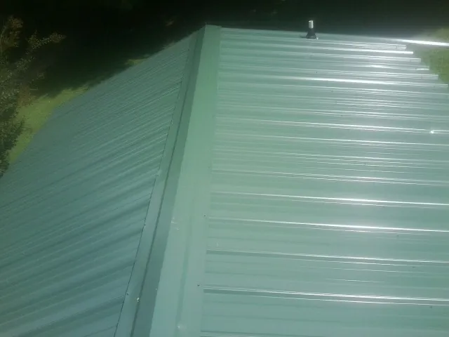 New green metal panels meeting at the ridge of a roof — Flat Roof Repair work by our crew in Sedro Woolley