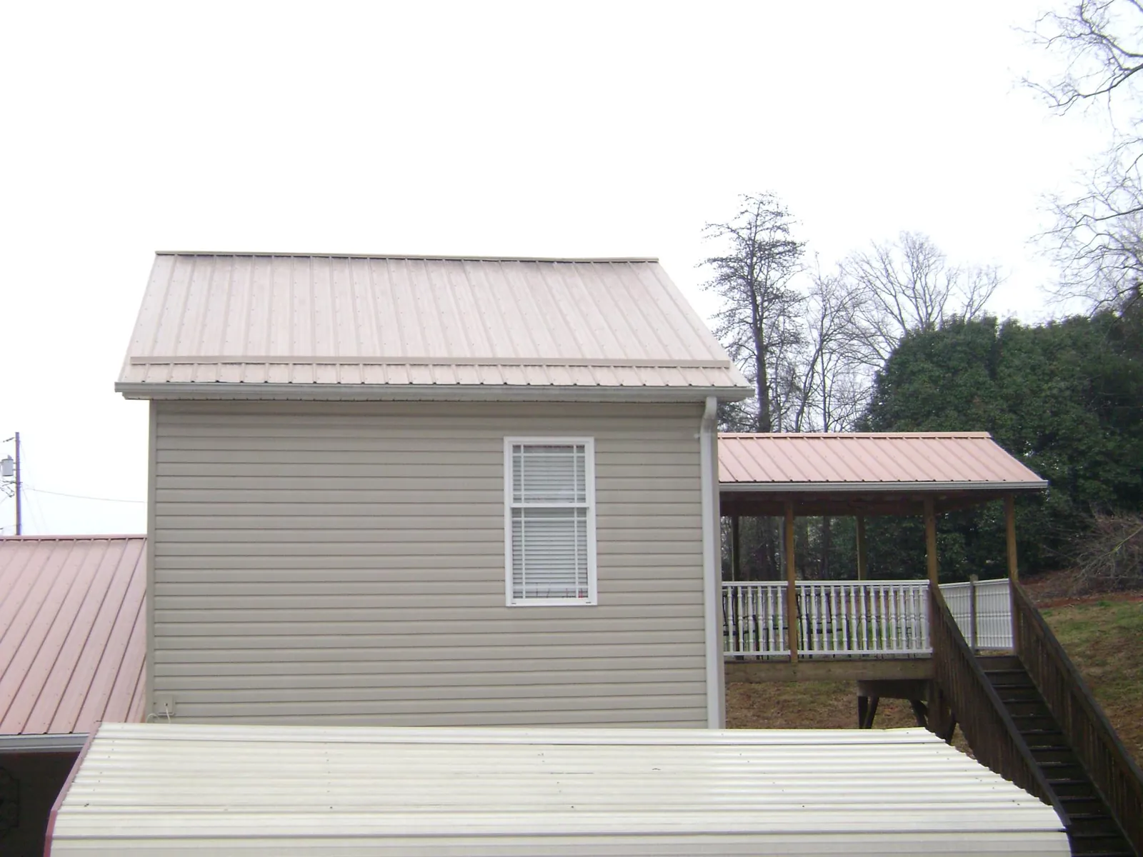 Tan metal roofs on a two story addition and attached porch, from a Roof Replacement job in Sedro Woolley