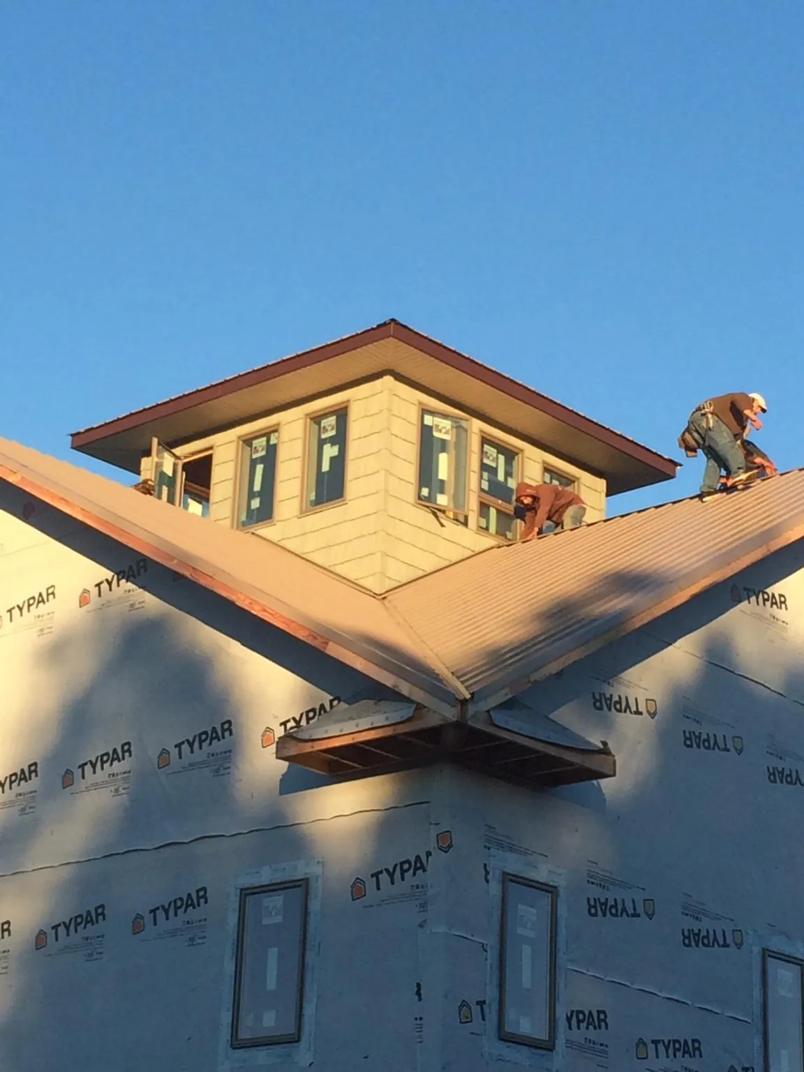Roofers working around a rooftop cupola on a new metal roof at sunset — Roof Waterproofing in Sedro Woolley by Roofing Brothers